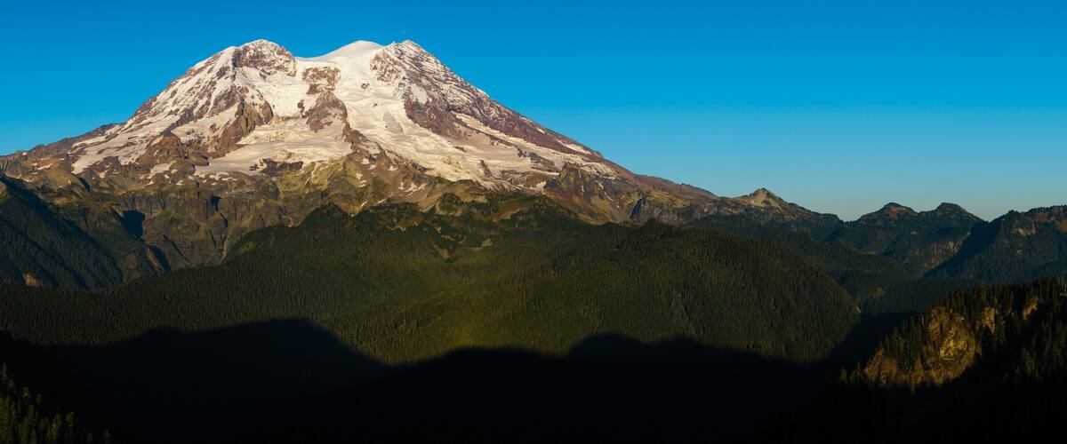 A snow-capped mountain with forested valleys.
