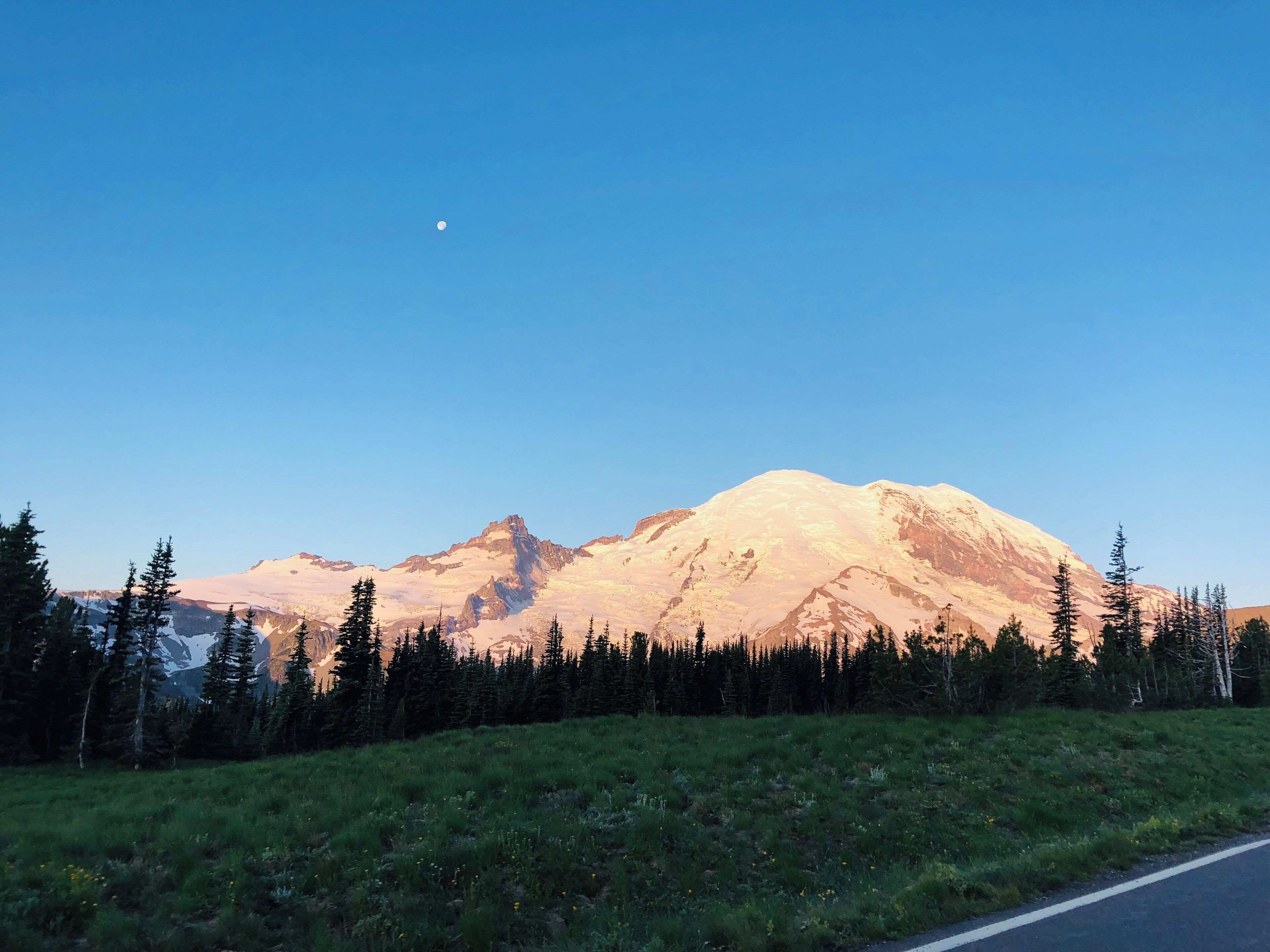 A mountain range with a clear sky and a crescent moon.