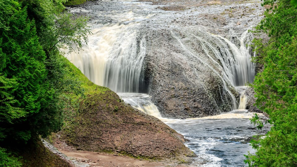 A multi-tiered waterfall surrounded by lush greenery.