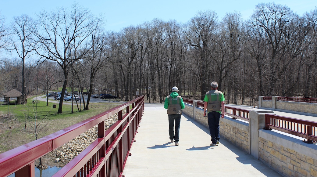 Two elderly male volunteers walking over a bridge over the DuPage River at McDowell Grove Forest Preserve in Naperville, Illinois