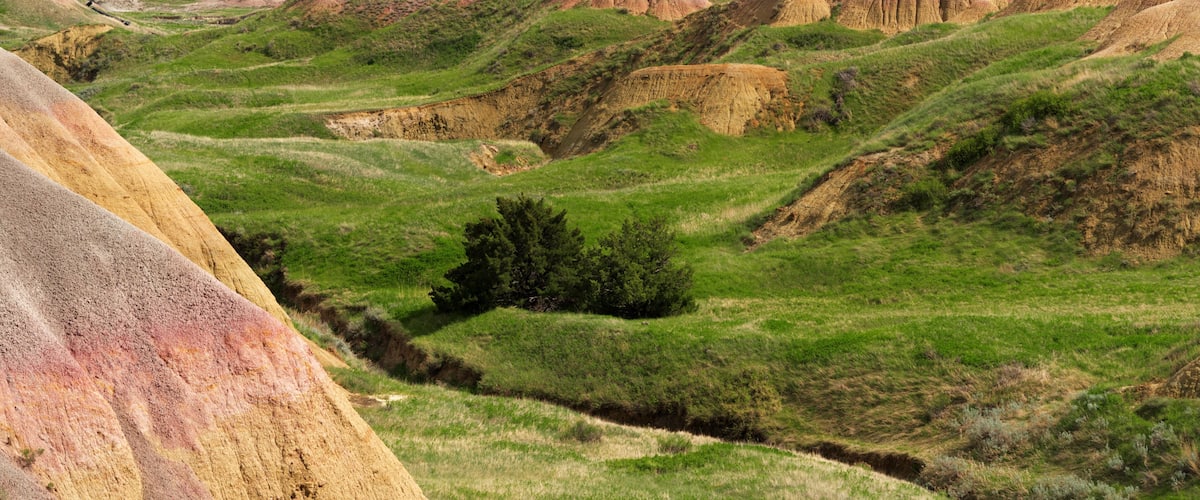 Rolling hills with colorful rock formations and green vegetation.