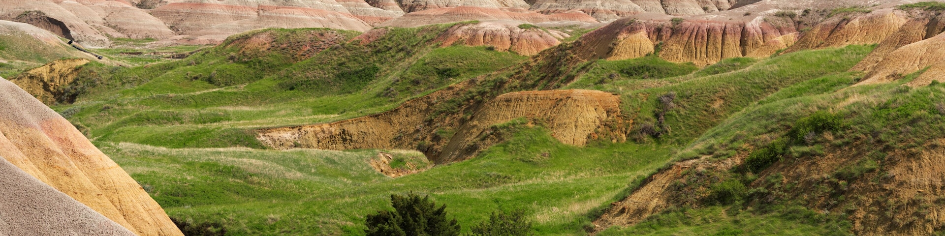 Rolling hills with colorful rock formations and green vegetation.