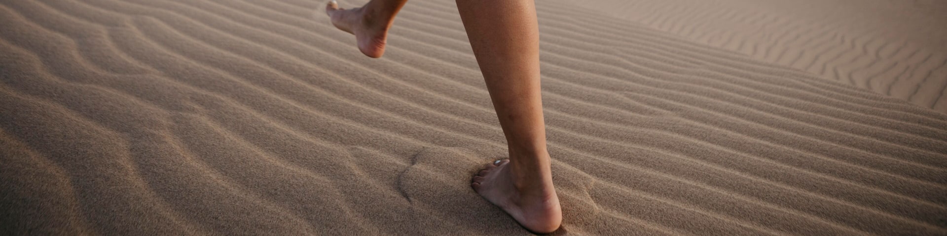 Crop view of woman walking barefoot on sand dune, Algodones Dunes, Brawley, USA