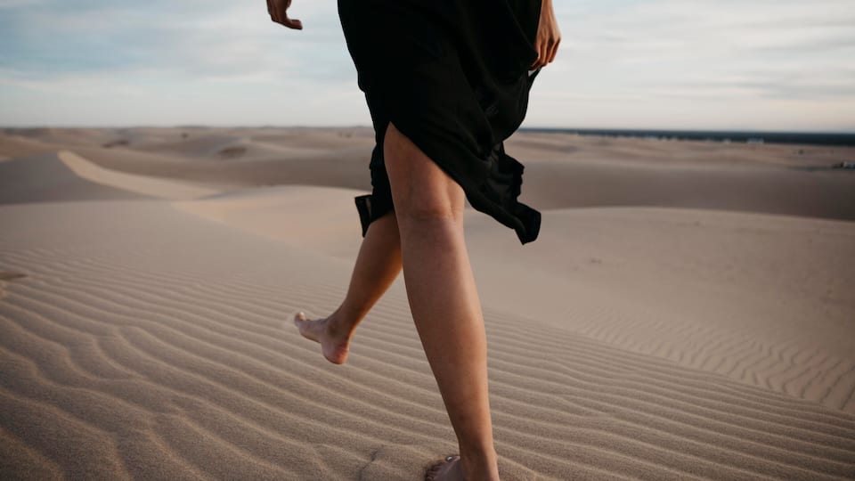 A person walking on a sandy desert landscape.