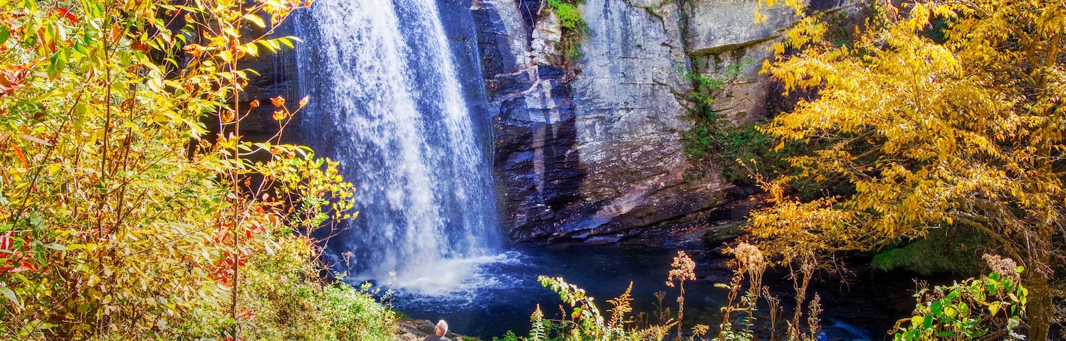 Una cascada se precipita por un acantilado rocoso rodeado de follaje otoñal.