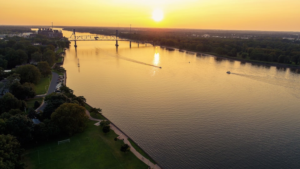 A river with a bridge, a park, and a cityscape in the background.