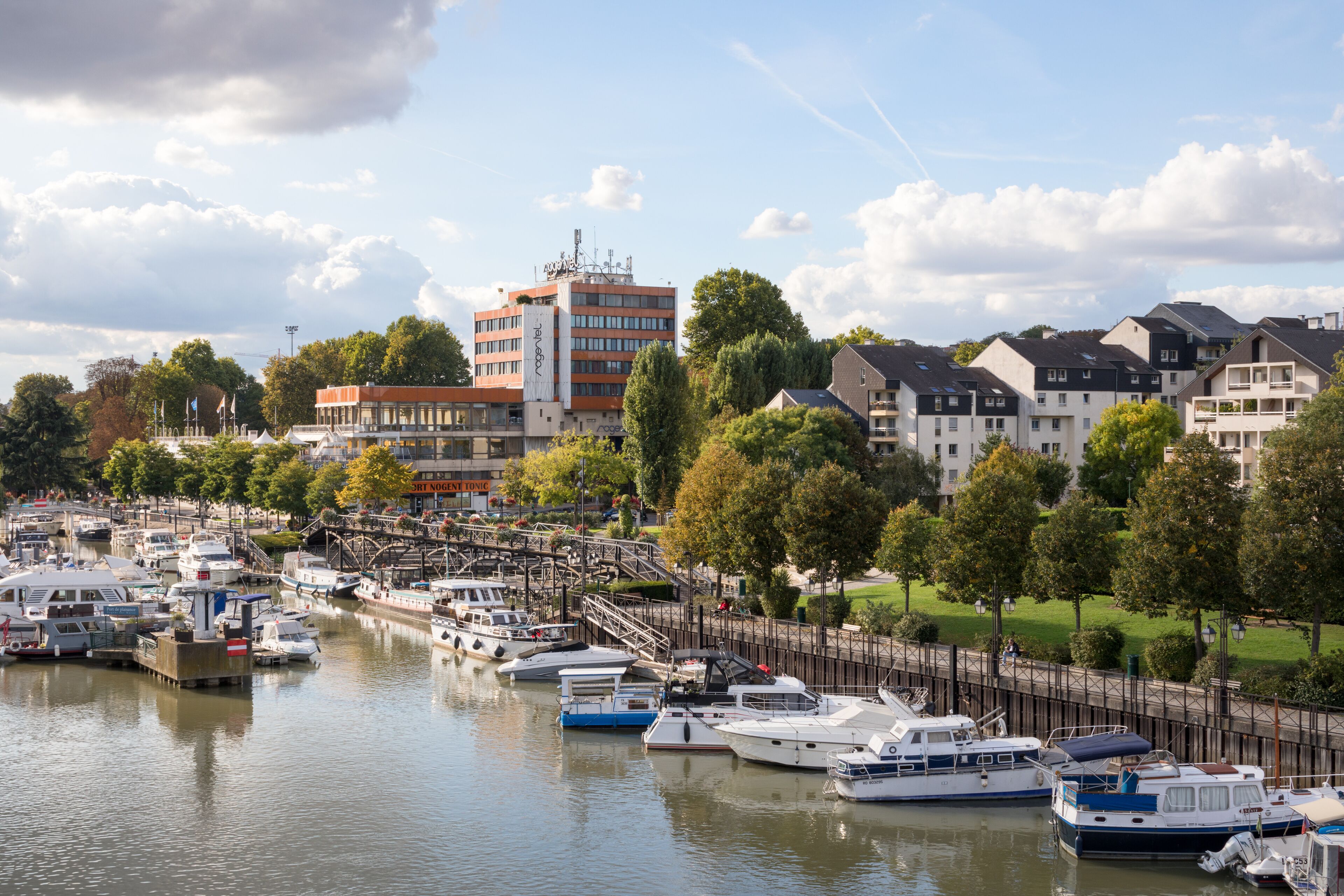 A marina with various boats docked, surrounded by residential buildings and trees.