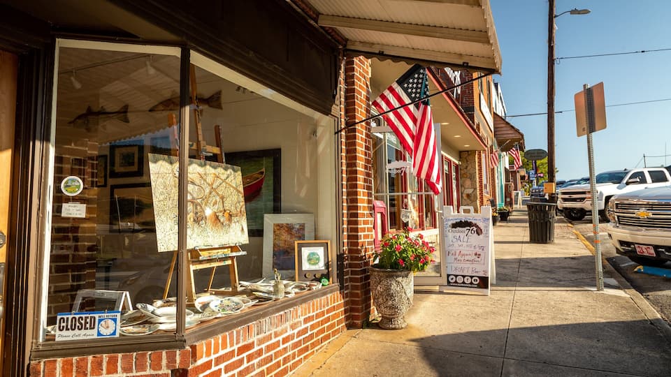 A storefront with American flags, a sign for an outdoor sale, and a closed sign.