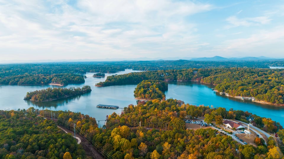A river winding through a forested area with several islands and a small settlement with buildings and vehicles.