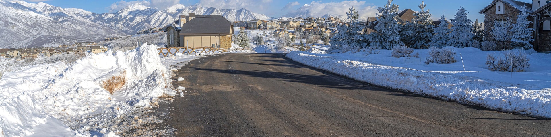 Snowy town with houses at Draper, Utah with snow plowed road and a view of Wasatch mountains