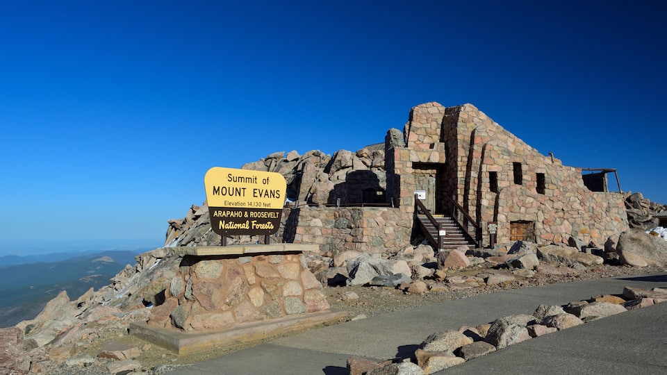 A stone building with a sign reading "Summit of Mount Evans, 14,130 feet, Arapahoe & Roosevelt National Forests."