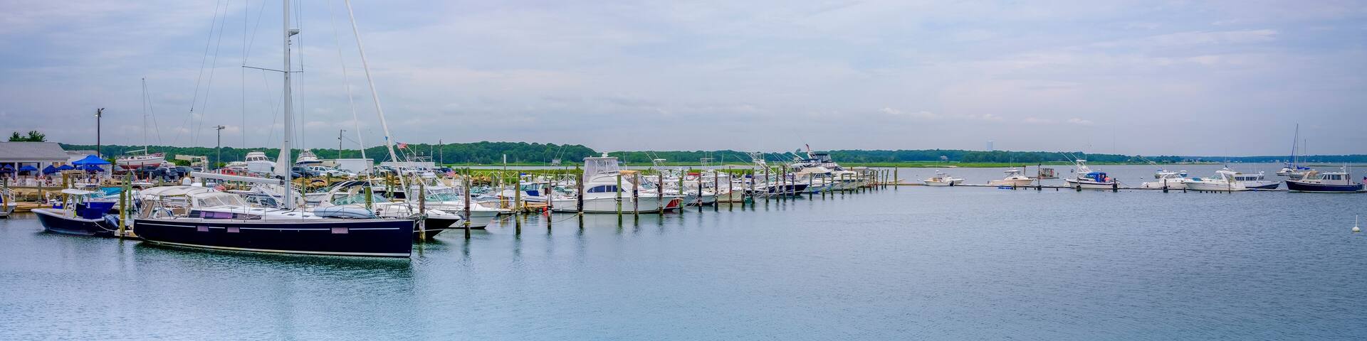 Panoramic seascape with moored boats and yachts under dramatic clouds in the summer. Post Covid-19 Summer at West Island Marina in Fairhaven, Massachusetts. Luxurious Lifestyle Image with Text Space.