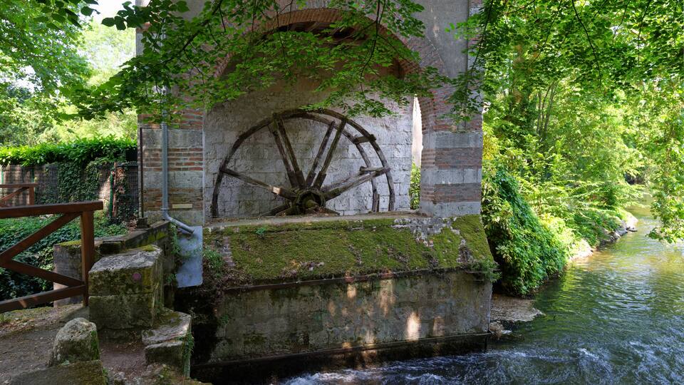 A historic water wheel in a lush green setting.