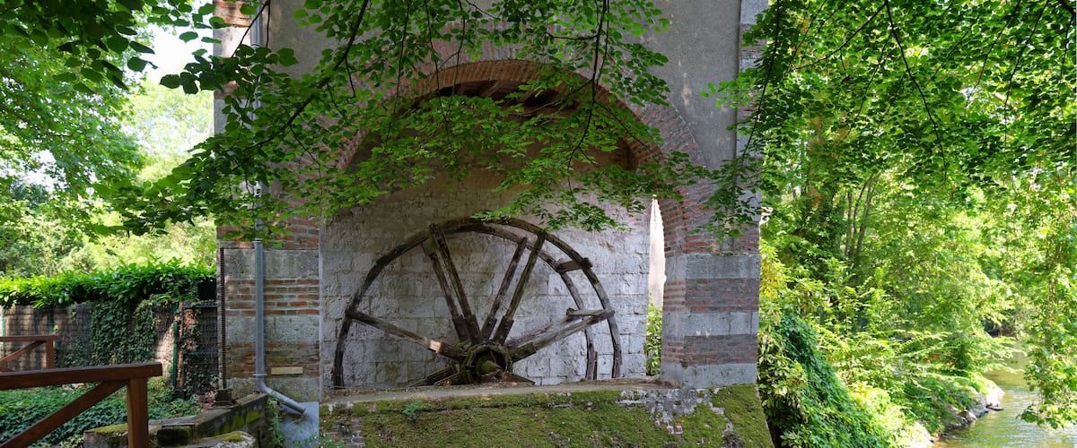 A historic water wheel in a lush green setting.