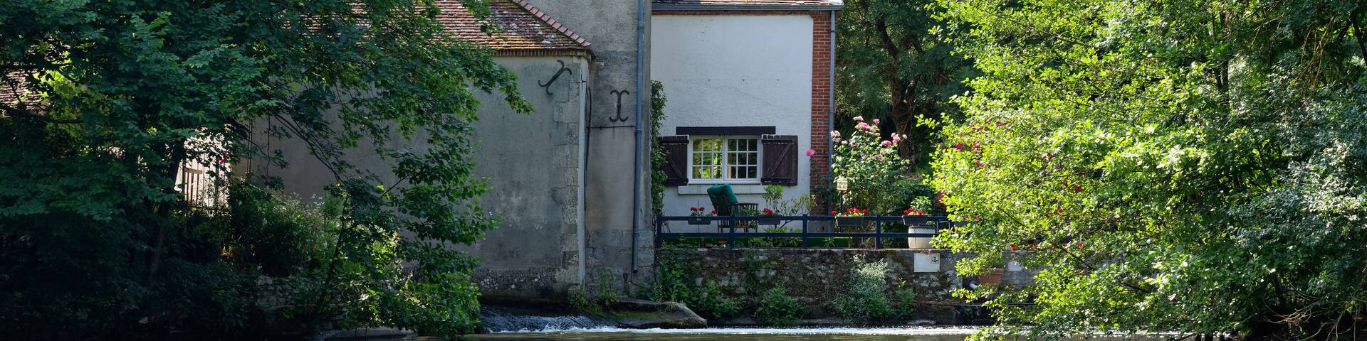 A riverside building surrounded by lush greenery.