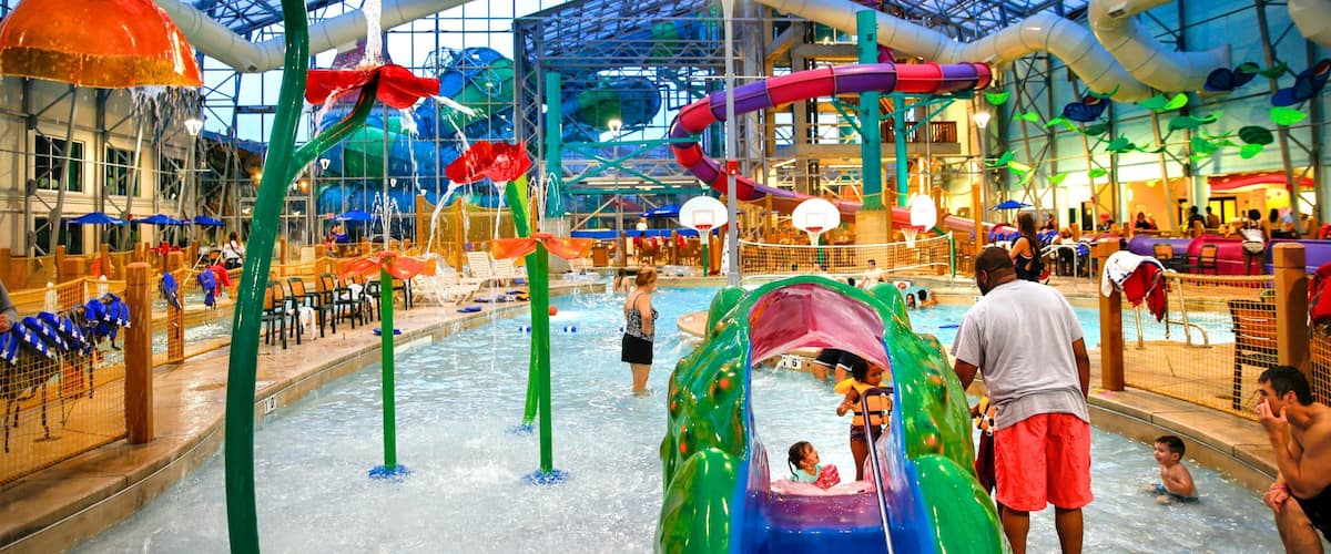 An indoor water park with slides, pools, and a large glass ceiling.