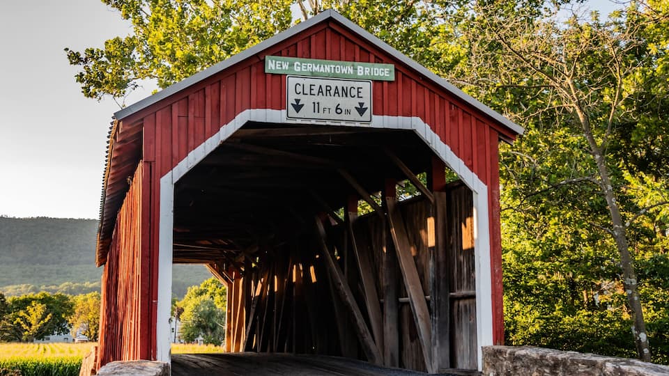 A red covered bridge with a sign indicating a clearance of 11 ft 6 in.