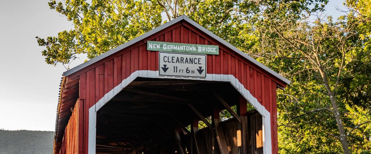 A red covered bridge with a sign indicating a clearance of 11 ft 6 in.