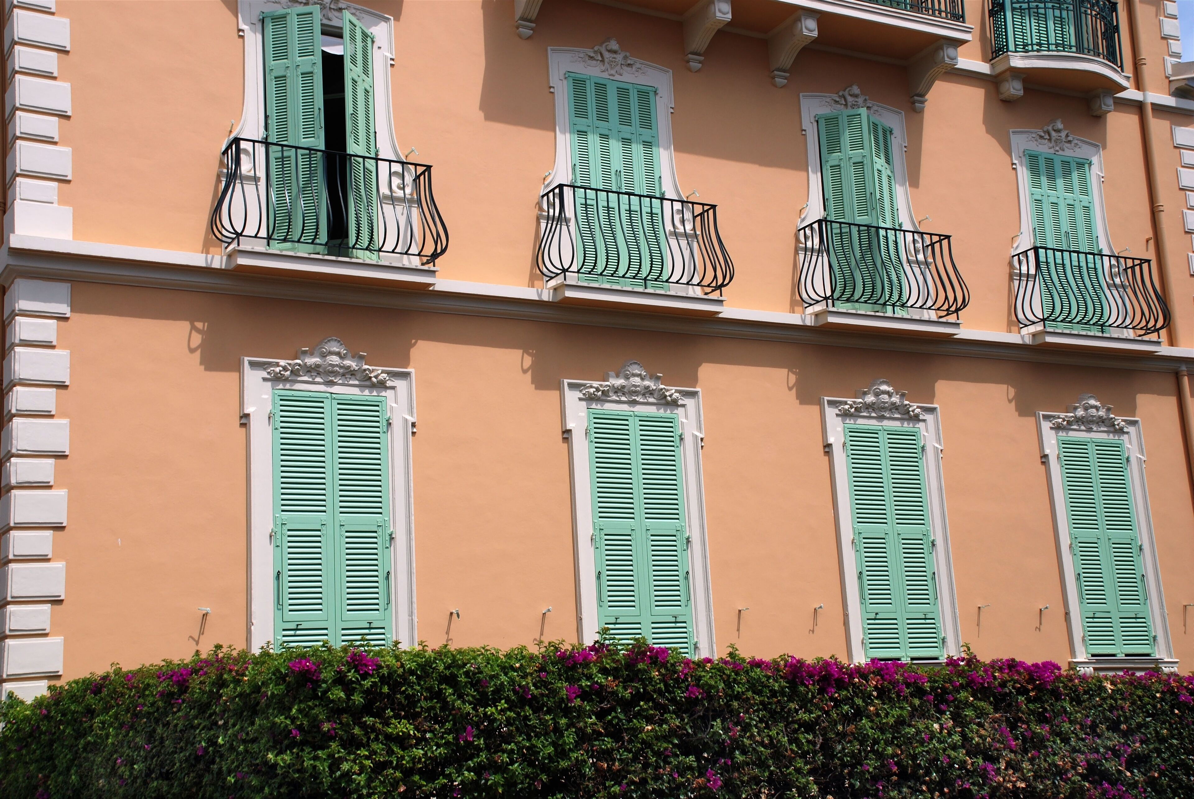 Un edificio con contraventanas verdes y balcones.
