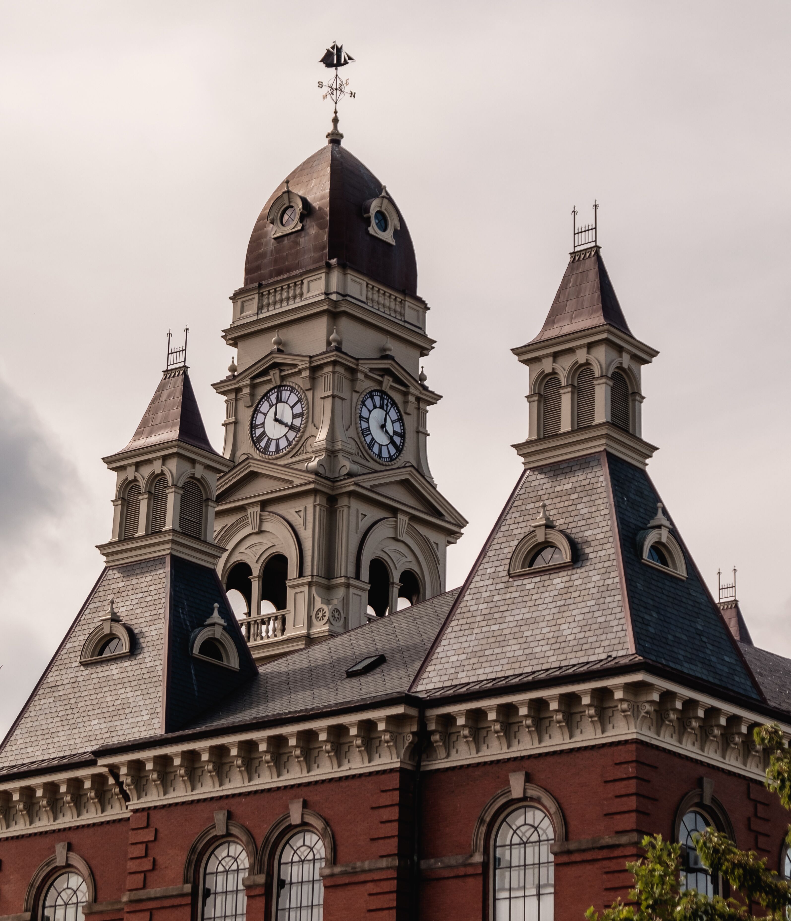 A historic building with a prominent clock tower, arched windows, and a weather vane.