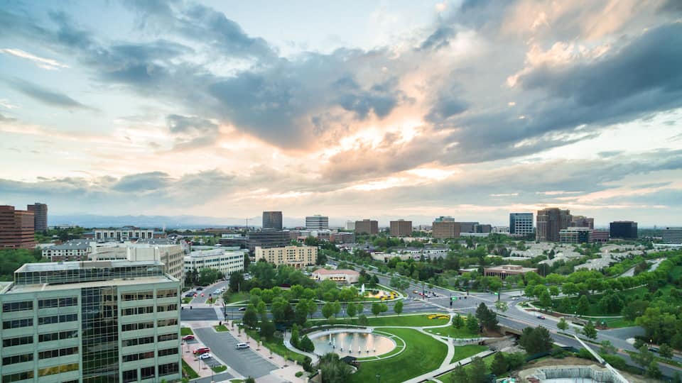 A cityscape with a large building, a roundabout, and a park with a fountain.
