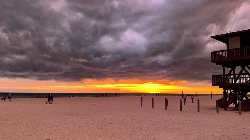 A beach with a lifeguard tower and a sunset.