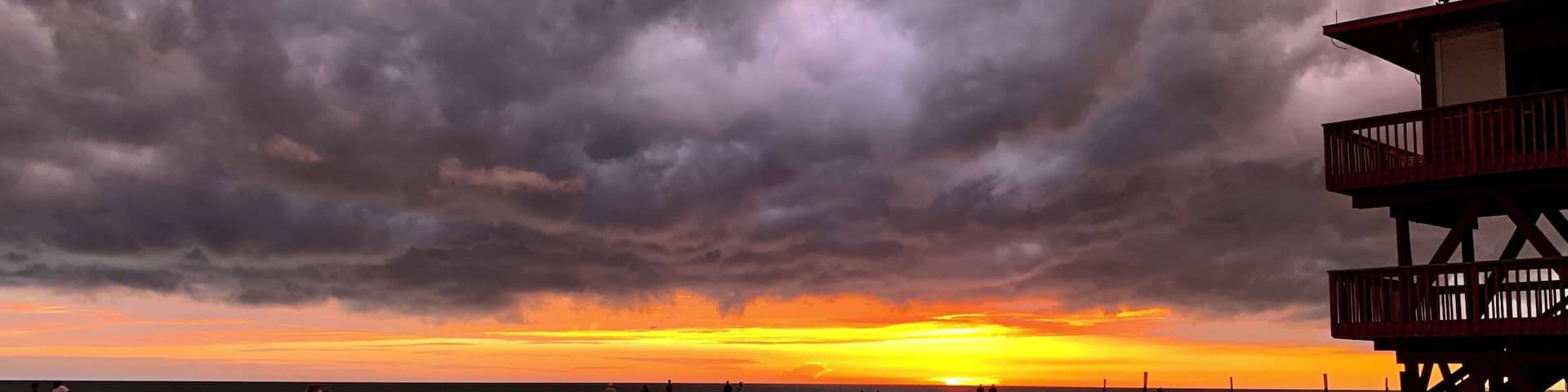 A beach with a lifeguard tower and a sunset.