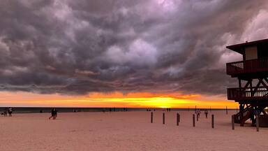 Uma praia com uma torre salva-vidas e um pôr do sol.