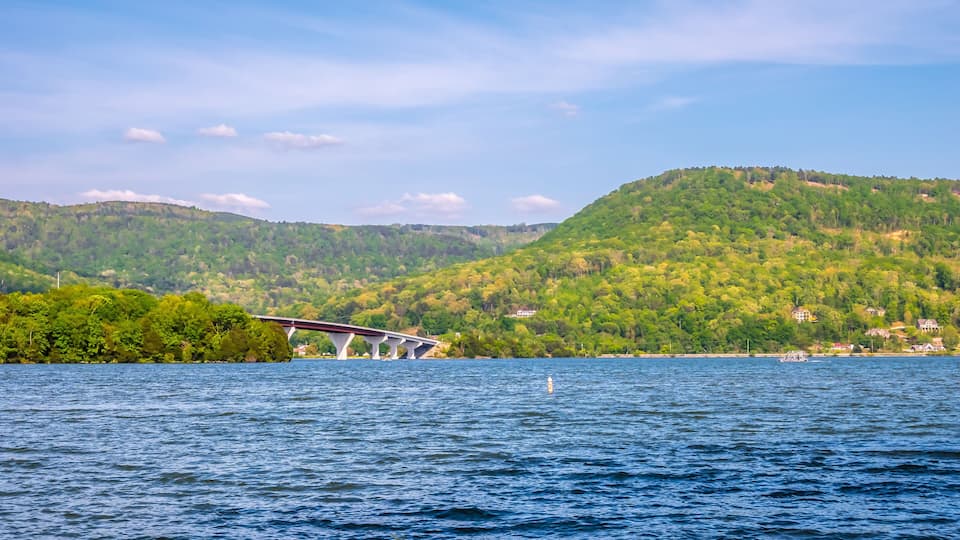 A bridge over a river with a forested hillside in the background.