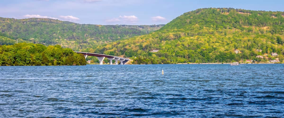 A bridge over a river with a forested hillside in the background.