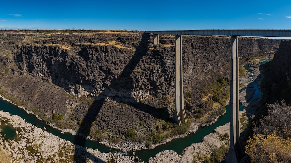A bridge over a deep canyon with a river below.