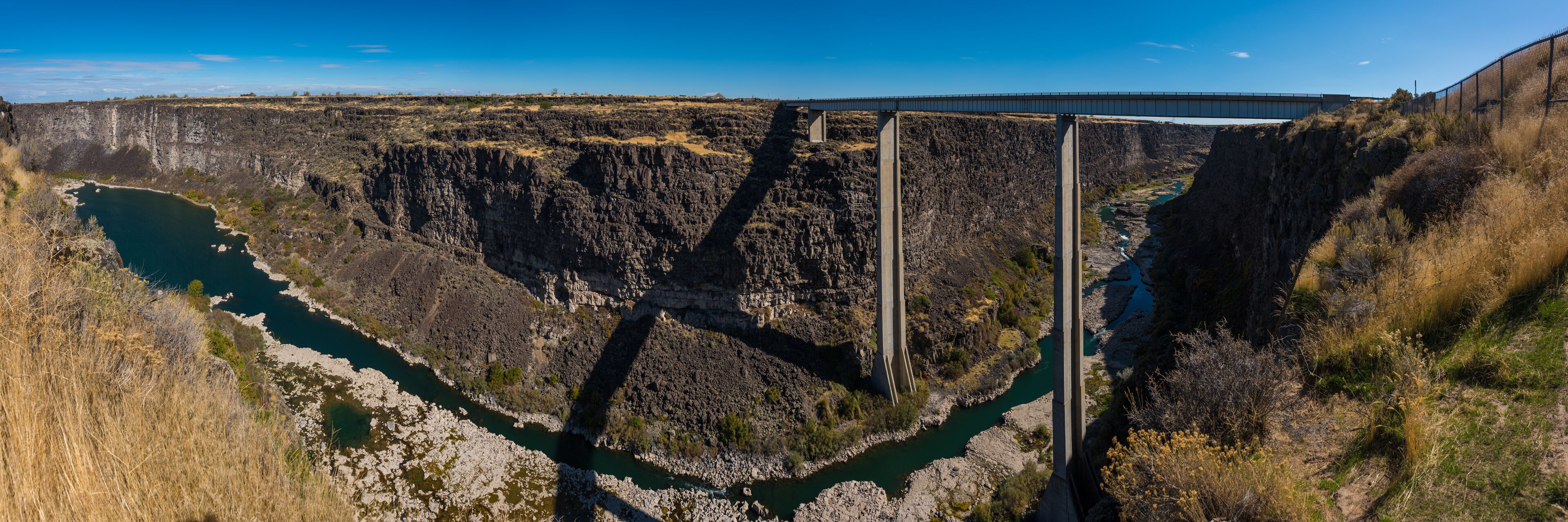 A bridge over a deep canyon with a river below.