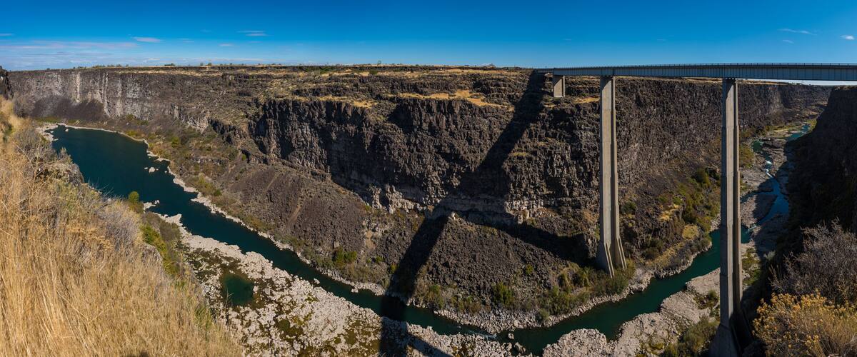 A bridge over a deep canyon with a river below.