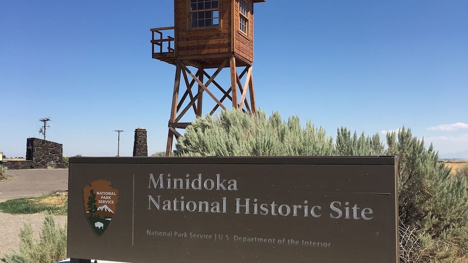 A wooden observation tower and a sign for the Minidoka National Historic Site.
