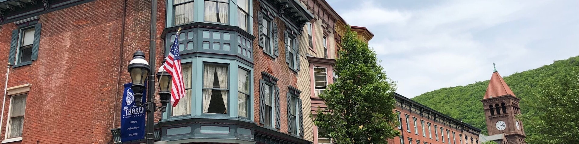 Um edifício histórico com uma torre de canto, bandeira americana e lojas antigas.