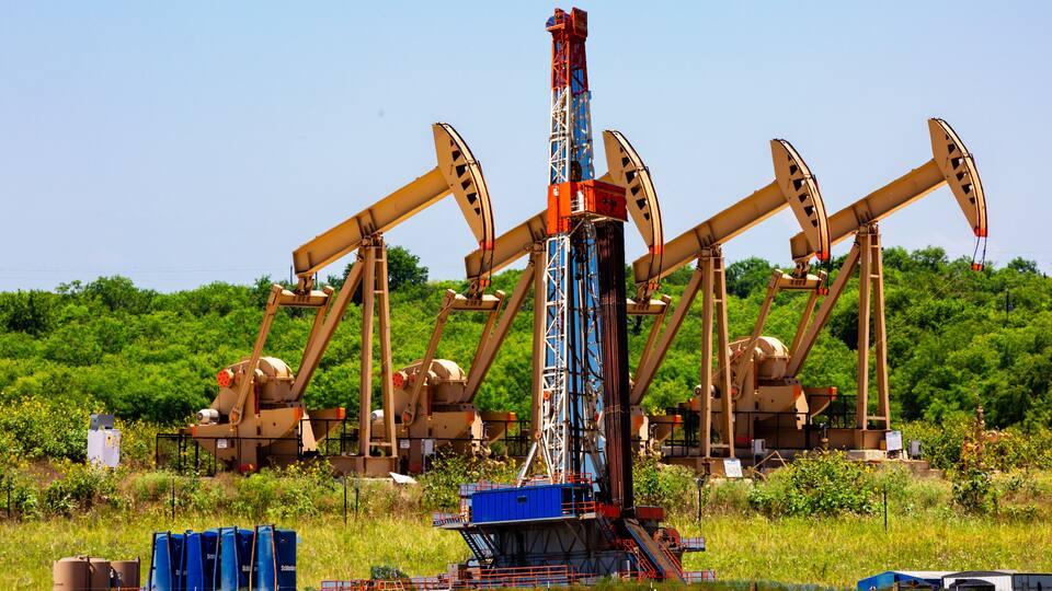Composite of pump jacks and drilling platform, Karnes County, Texas.