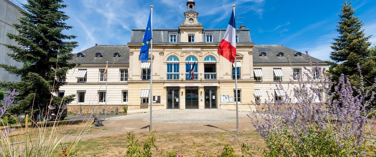 A historic building with flags, a cobblestone courtyard, and surrounding trees.