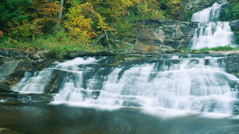 A multi-tiered waterfall surrounded by autumn foliage.
