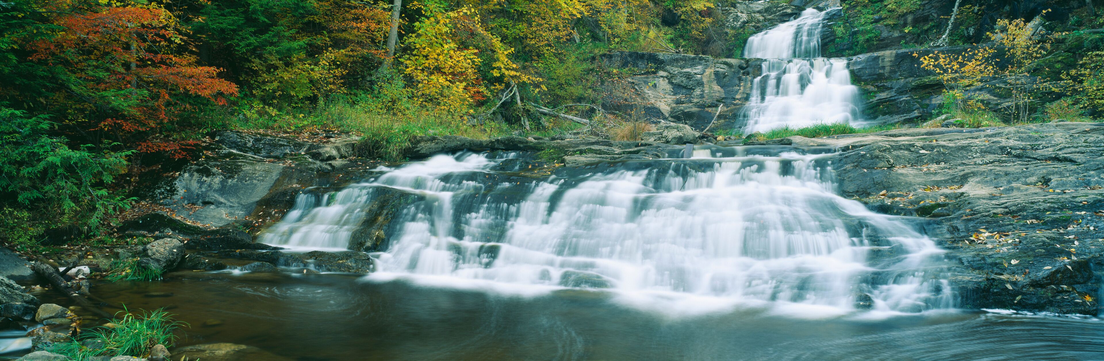 A multi-tiered waterfall surrounded by autumn foliage.