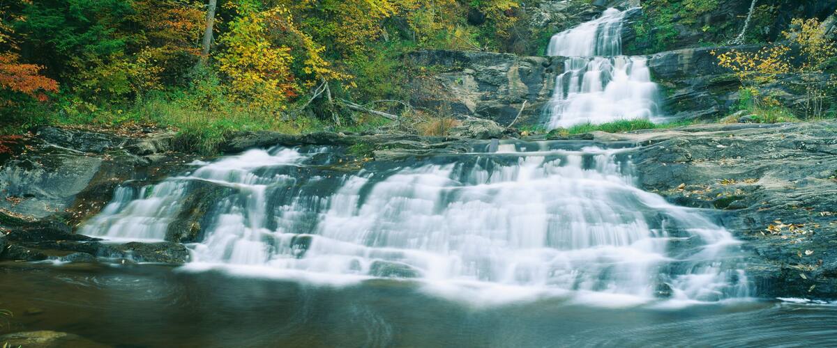 A multi-tiered waterfall surrounded by autumn foliage.