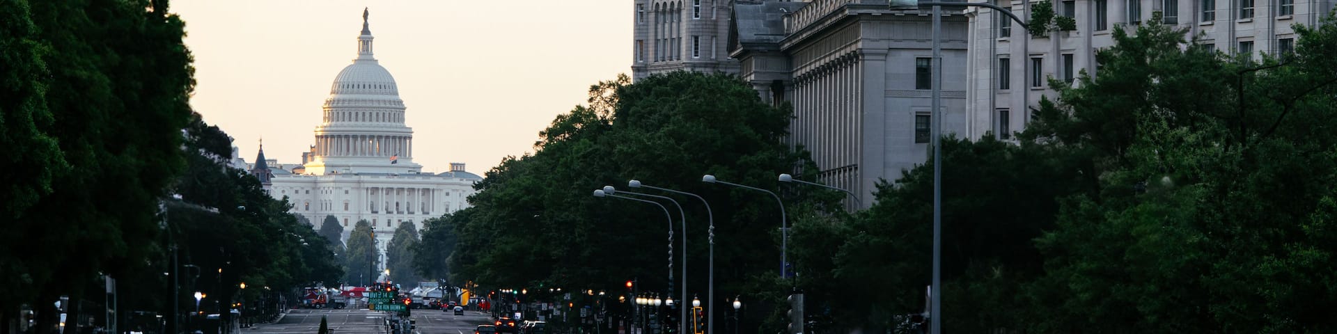 A cityscape with a prominent clock tower, a large dome building, and a flag.