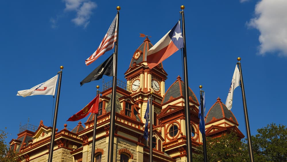 Un bâtiment historique orné de plusieurs drapeaux, dont le drapeau américain, et surmonté d’une tour horloge.