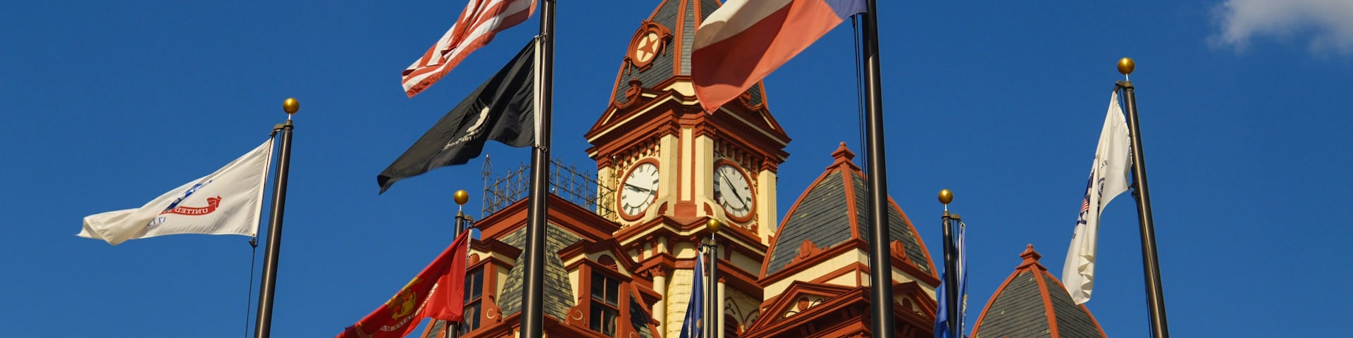 A historic building with multiple flags, including the American flag, and a clock tower.