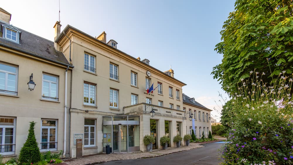 Un bâtiment historique doté d’une horloge, d’un drapeau et d’un jardin bien entretenu.