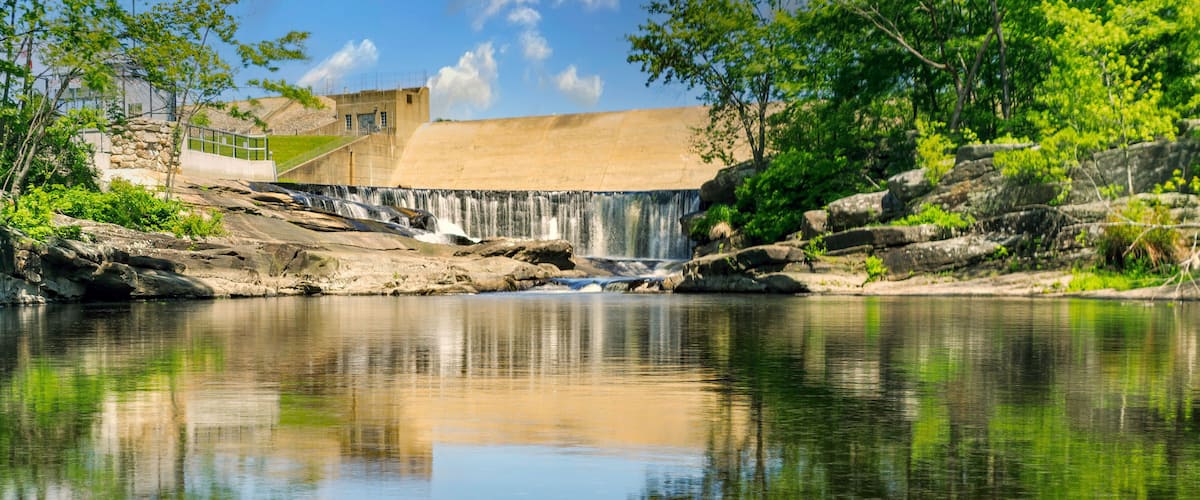 A waterfall, a stone building, and a calm river.