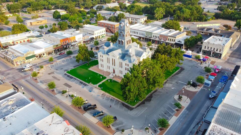 An aerial view of a town with a prominent church with a clock tower, surrounded by streets and buildings.