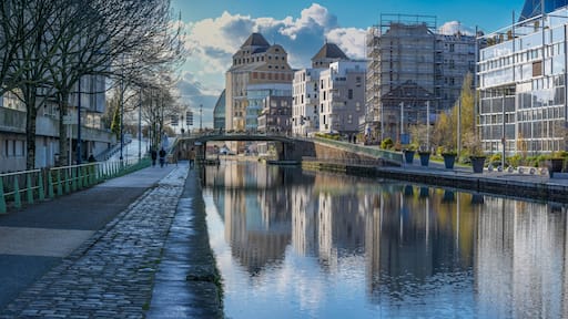 Paris, France - 03 14 2026: Ourcq Canal. Panoramic view of Les Grands Moulins of Pantin, City Hall Footbridge and buildings reflecting on the water