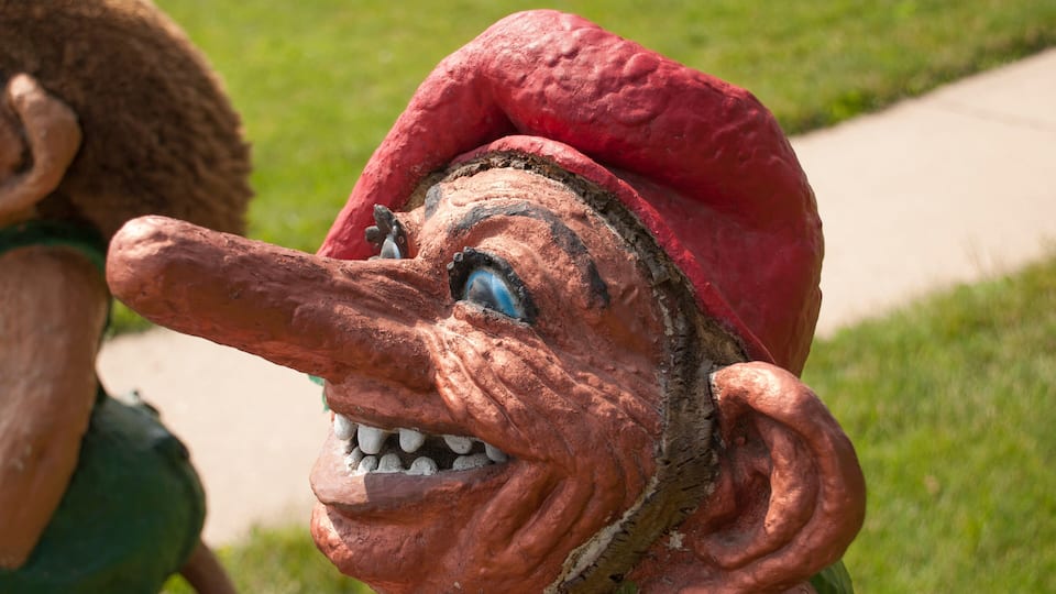 A close-up of a statue with a red hat and a large nose.