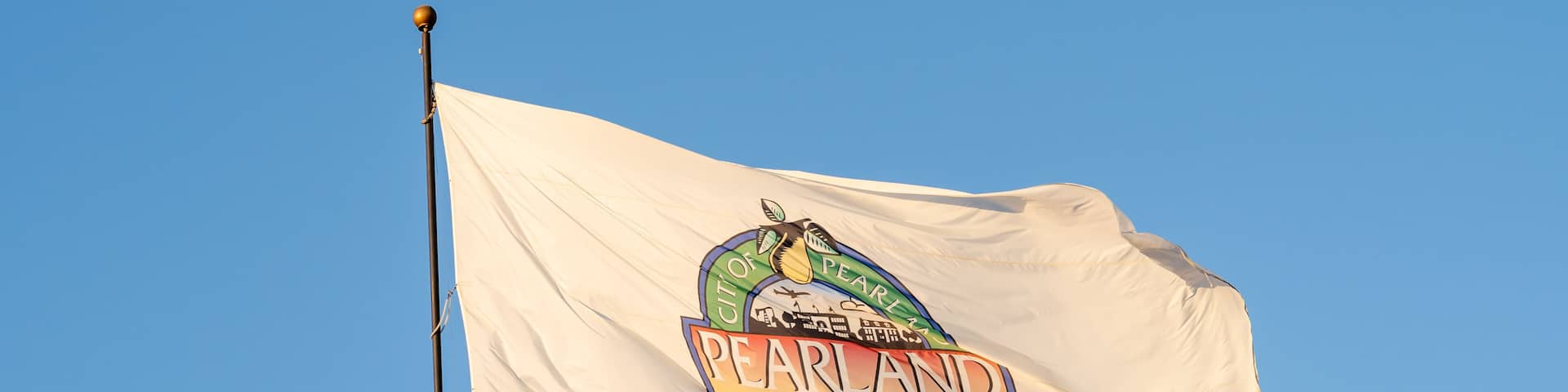 Flag of Pearland waving in the wind with blue sky in background. Pearland is a city in the U.S. state of Texas.