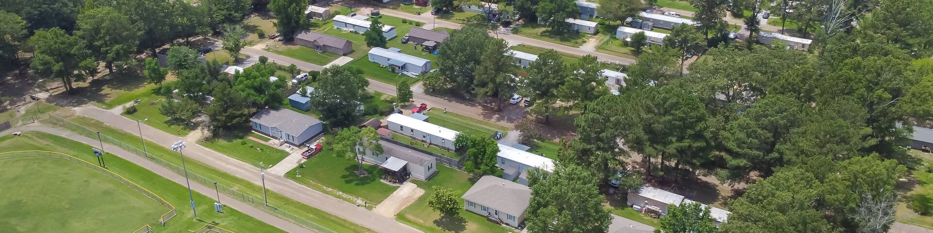 Large baseball fields near row of manufactured, modular, and mobile homes in Richland, Rankin County, Mississippi suburb of Jackson, lush green trees neighborhood